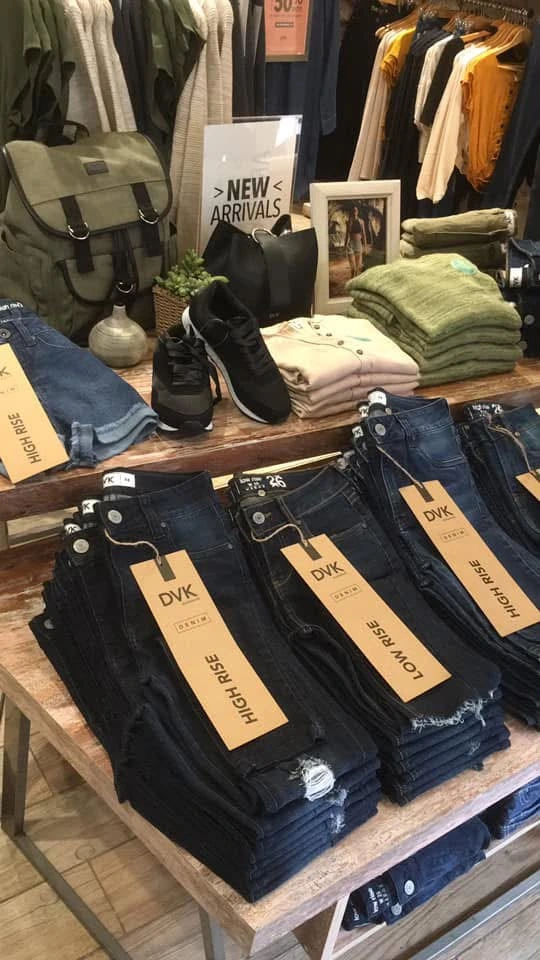 DVK — mesa comercial de denim y accesorios organizada por producto, altura y lectura visual.